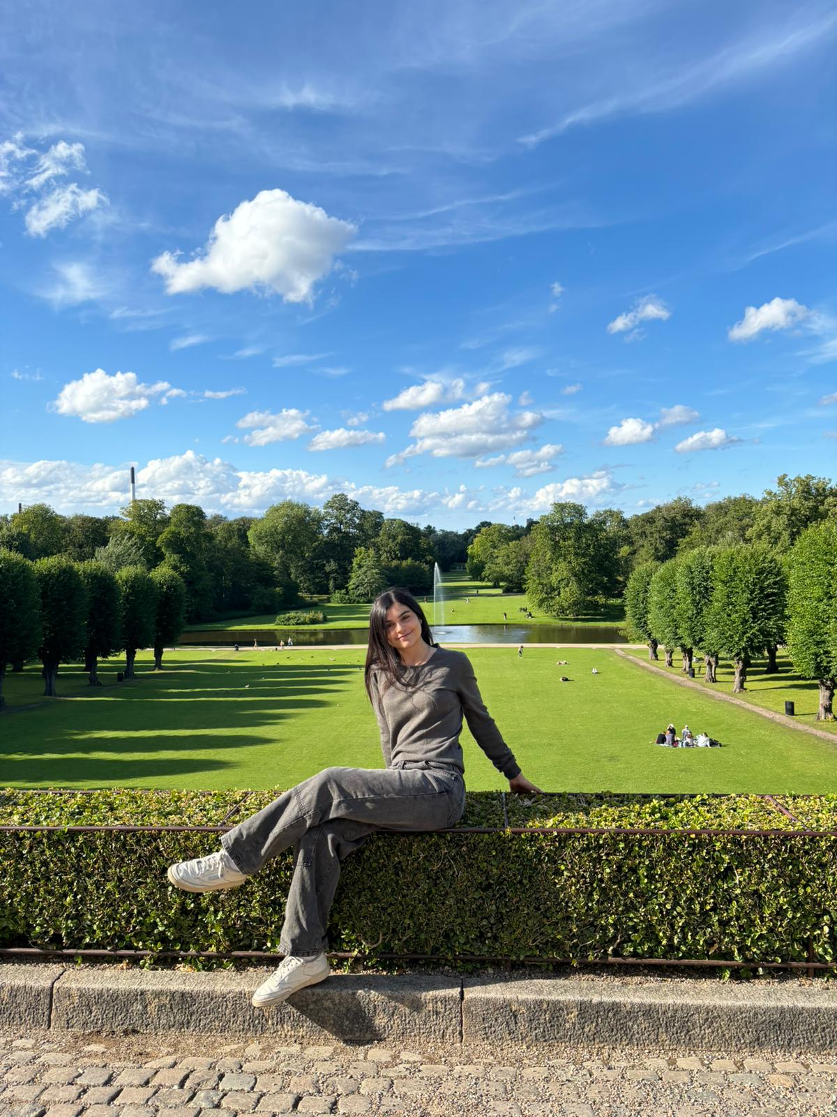 Valentina sitting on a hedge in a Copenhagen park
